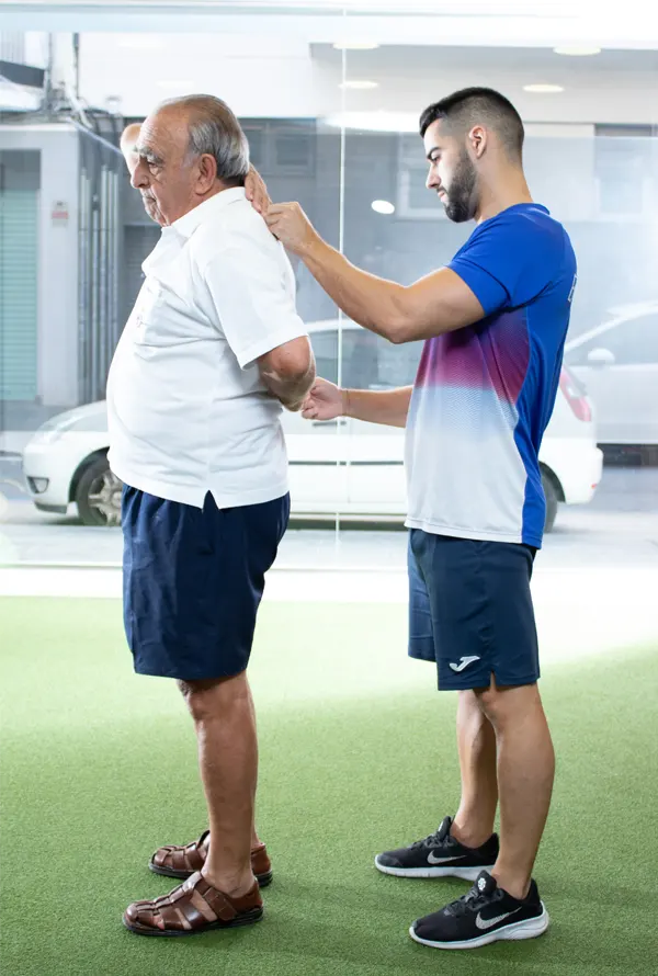 Entrenador ayudando a realizar un ejercício de brazos a un hombre mayor